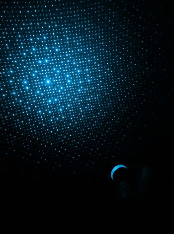 Blaues Lichtmuster aus vielen kleinen leuchtenden Punkten auf dunklem Hintergrund.