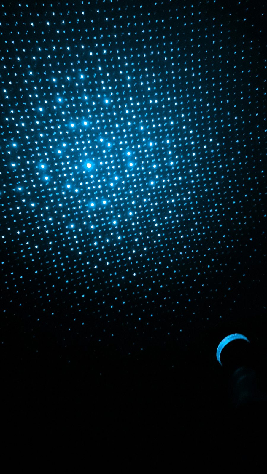 Blaues Lichtmuster aus vielen kleinen leuchtenden Punkten auf dunklem Hintergrund.